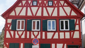 Une maison traditionnelle à colombages, avec un clocher en arrière-plan.