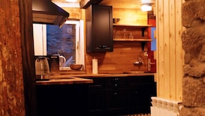 Une cuisine étroite avec des poutres en bois, un carrelage à motifs et un mur en pierre.