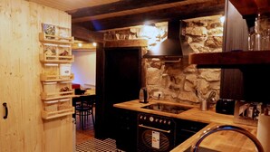 Une cuisine rustique avec un mur en pierre, des étagères en bois et un four encastré.