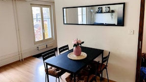 Un comedor con una mesa, sillas, un jarrón de flores y un espejo grande en la pared.
