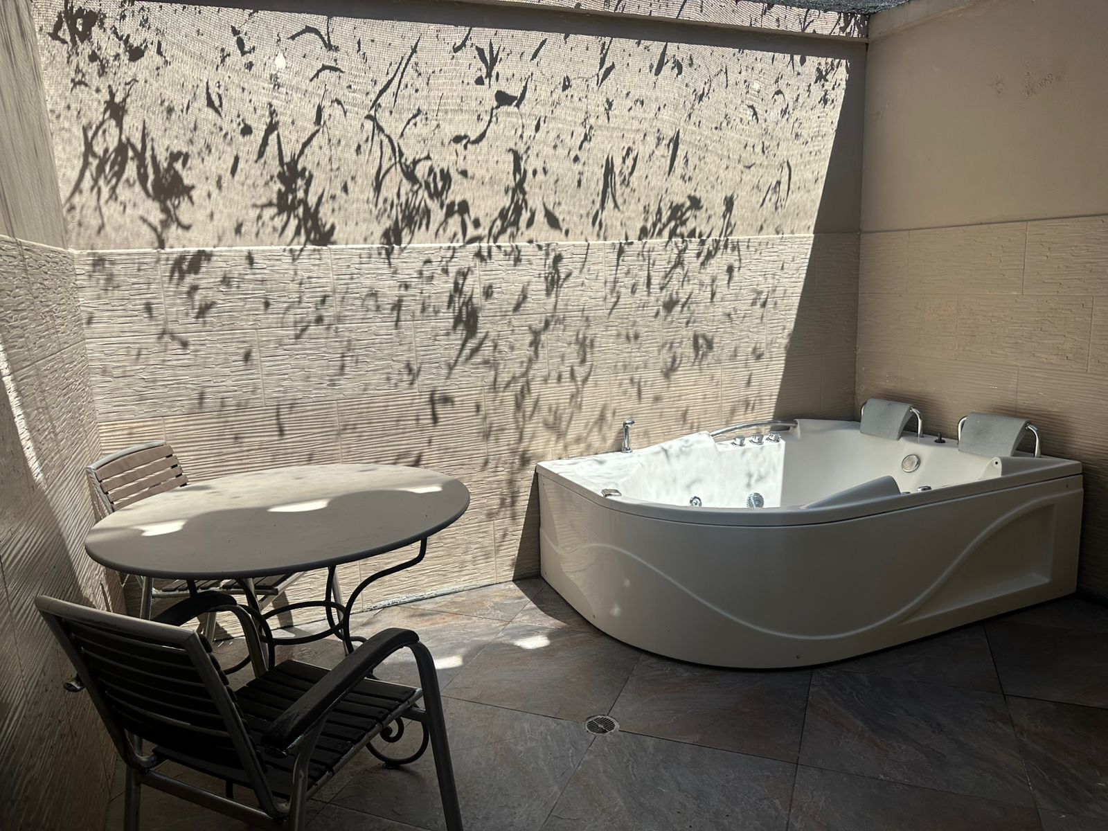 A modern bathroom with a freestanding bathtub, a small table, and two chairs.