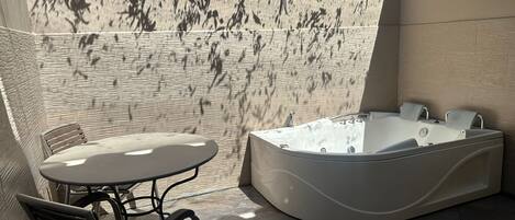A modern bathroom with a freestanding bathtub, a small table, and two chairs.