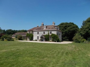 A large, two-story stone house with a symmetrical facade, a central entrance, and a well-maintained lawn in front. - Manor House Moreton - Entire Holiday Home (Dorchester)