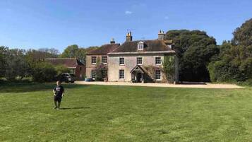 A large, historic house with a spacious lawn in front.