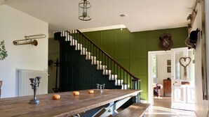 A dining area with a wooden table and benches, a staircase with green walls, and a door with a heart decoration. - Manor House Moreton - Entire Holiday Home (Dorchester)