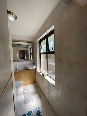 Une petite salle de bain avec des toilettes, un lavabo et une fenêtre.
