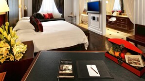 A hotel room with a large bed, a TV, a desk with a book, and a red side table with fruits and a postcard. - If you Like it, Stay If you Dont Like it, Just Stay (Hanoi)