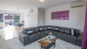 Ein modernes Wohnzimmer mit einem dunkelbraunen Ledersofa, einem Glastisch und einem Stadtbild an der Wand.