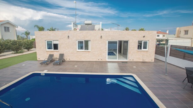 Ein modernes Haus mit Swimmingpool, überdachter Terrasse und Meerblick.