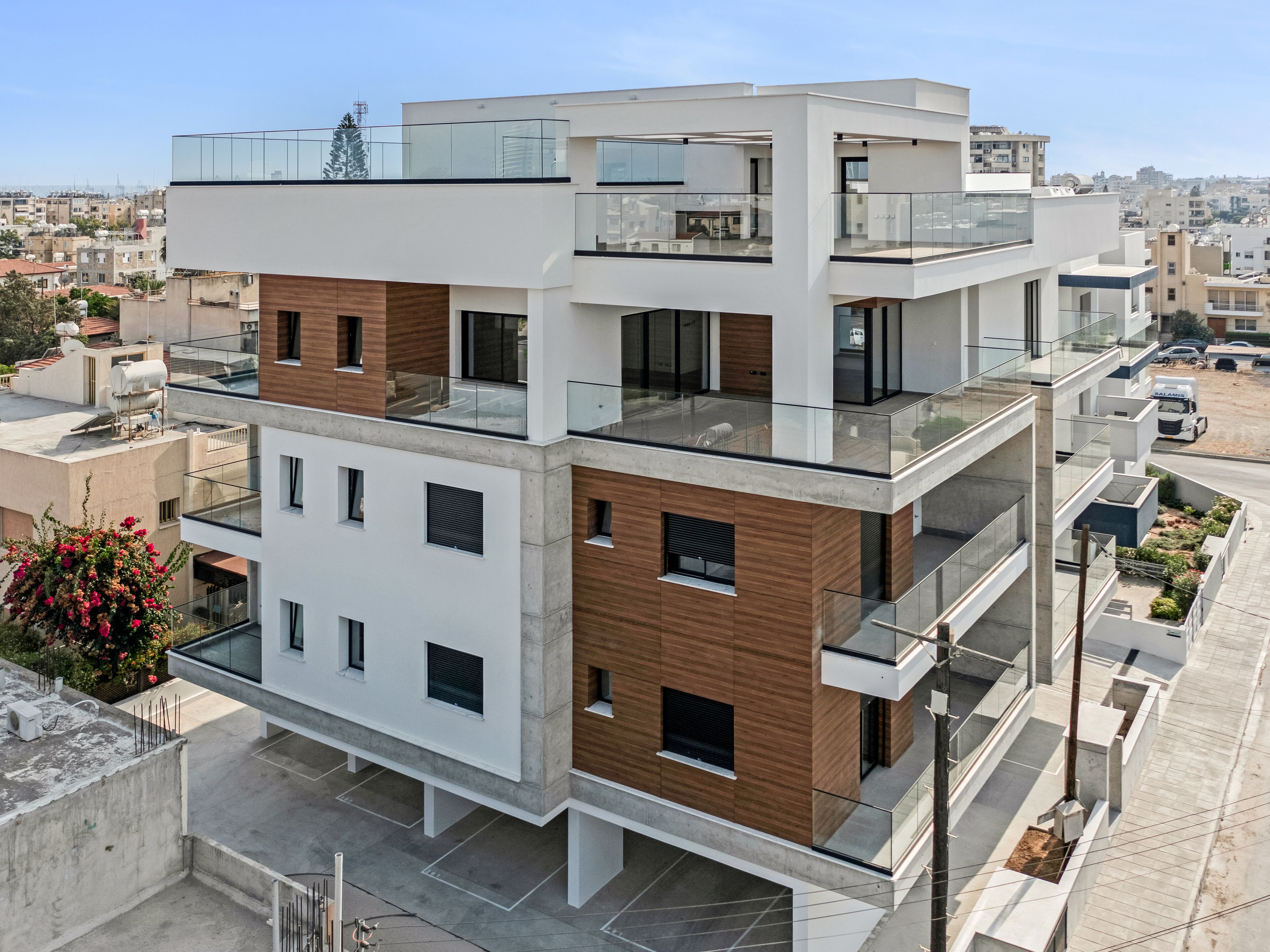 A modern multi-story residential building with a flat roof, large windows, and balconies.