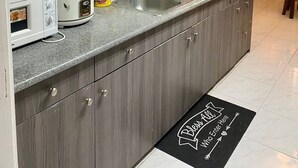A modern kitchen with grey cabinets, a granite countertop, a sink, a microwave, and a slow cooker. - House w 3 Bedrooms And 3 Baths - Free Parking (Olongapo)