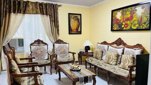 A traditional living room with ornate furniture, a large painting, and a vase on the wall. - House w 3 Bedrooms And 3 Baths - Free Parking (Olongapo)
