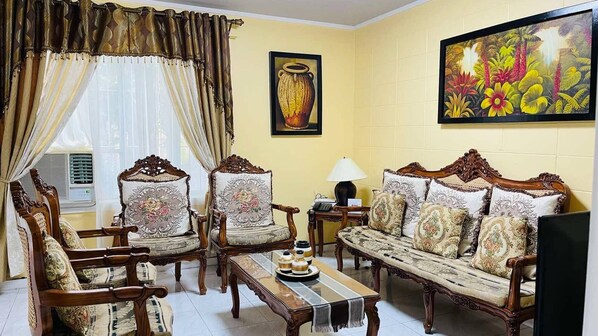 A traditional living room with ornate furniture, a large painting, and a vase on the wall.
