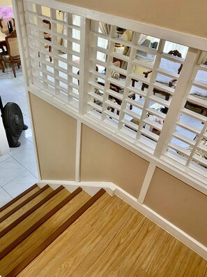 Eine Holztreppe mit weißer Geländer, die zu einem Raum mit Blick auf einen Balkon führt.