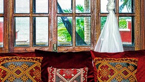 A room with a large window, a bed with a red headboard, and two decorative pillows.