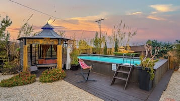Relax in a serene outdoor setting with a hot tub and lounge chair amidst lush greenery.