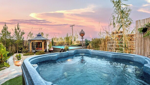 A hot tub surrounded by a garden with a gazebo, a wooden fence, and a pool. - Casa Luisa Joshua Tree (Joshua Tree)