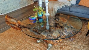 A glass coffee table with a unique wooden base, a blue plant, and three white candles. - Casa Luisa Joshua Tree (Joshua Tree)