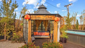 A gazebo with a wooden bench and a pool in the background. - Casa Luisa Joshua Tree (Joshua Tree)