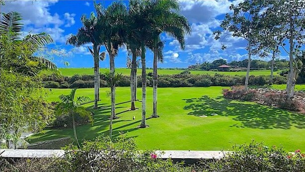 A golf course with a well-maintained green, palm trees, and a stone wall. - Srvittinivillas Aptla/ Best View/ Fam/couple/ Team/ Work Tr/ Casa de Campo Rv (La Romana)