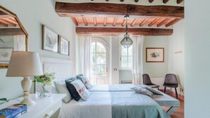 A bedroom with a bed, bedside tables, a lamp, and framed pictures on the walls. - Elisa Farmhouse Apartment in Wine Resort (Lucca)