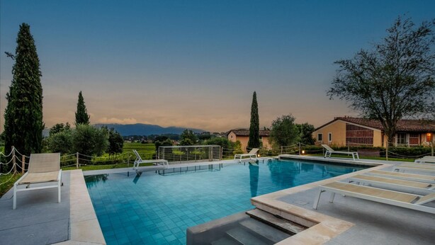 A swimming pool with lounge chairs and a view of the mountains. - Elisa Farmhouse Apartment in Wine Resort (Lucca)