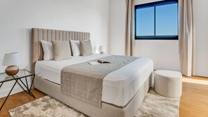 A modern bedroom with a large bed, a bedside table, a lamp, and a window with curtains. - Sanders Crystal 2 - Dreamy 3-bdr. Apt. With Shared Rooftop (Limassol)
