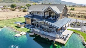 Et stort hus med pool, udendørs møbler og udsigt over det omkringliggende landskab.