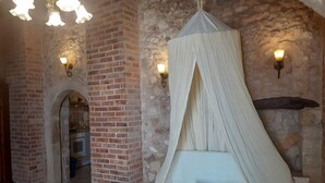 Une pièce avec un mur en briques, un lit à baldaquin et deux lampes fixées au mur.
