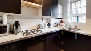 Een moderne keuken met donkere kastjes, een gasfornuis, een magnetron, een koffiezetapparaat en een vaatwasser.