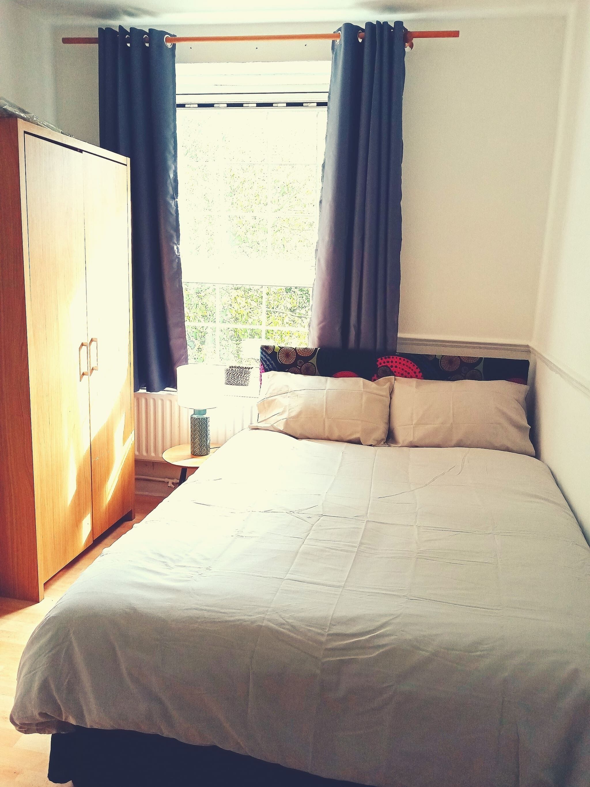 Une chambre à coucher avec un lit, une armoire et une fenêtre avec des rideaux.