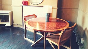 Een ronde houten tafel met vier stoelen, een lamp en een ronde spiegel aan de muur.