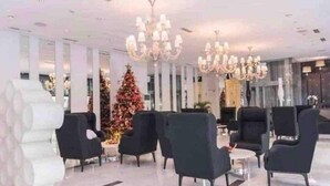 Eine moderne Lobby mit schwarzen Sesseln, einer großen Weihnachtstanne und Kristalllüstern.