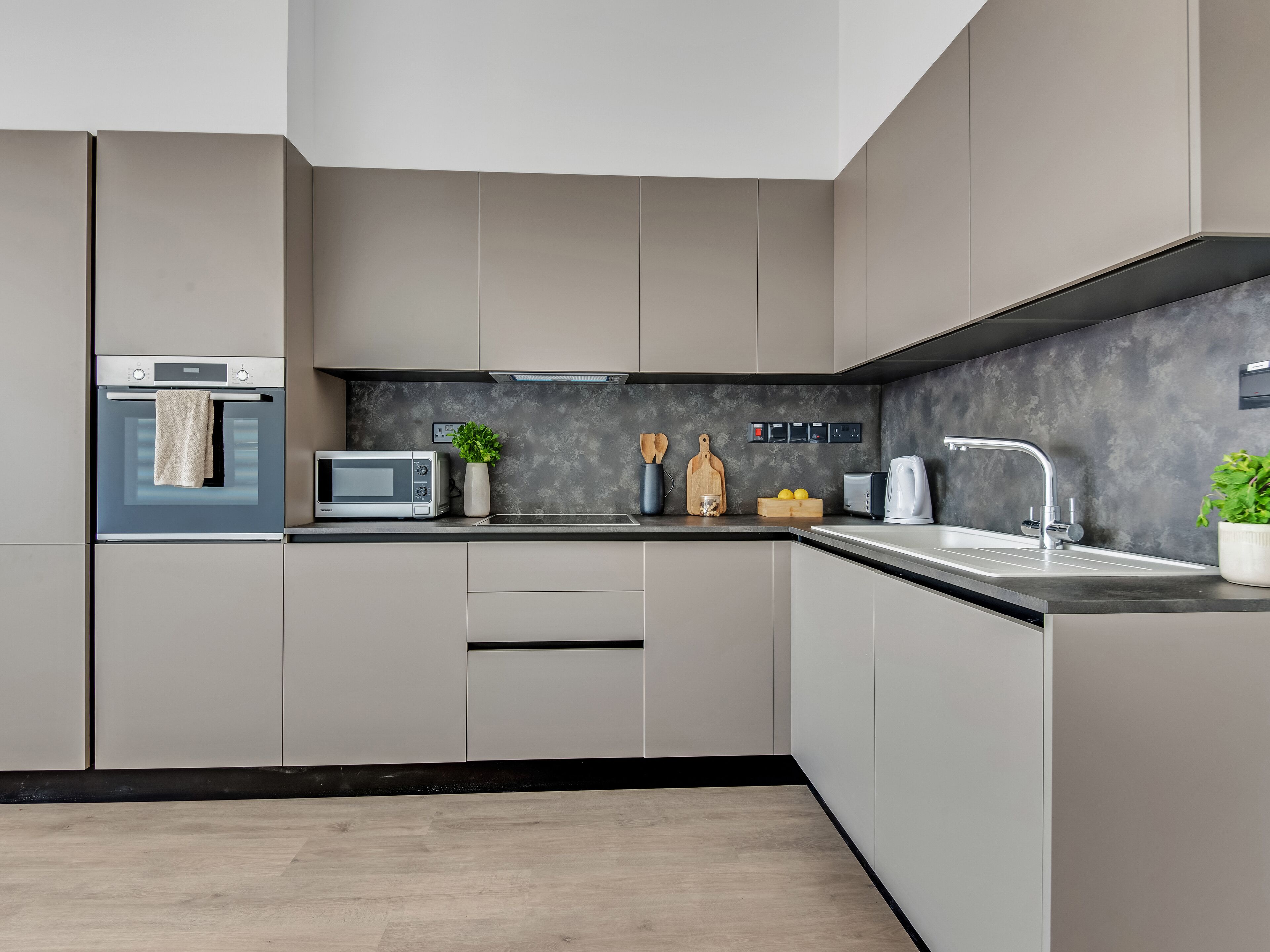 A modern kitchen with a built-in oven, microwave, and sink.