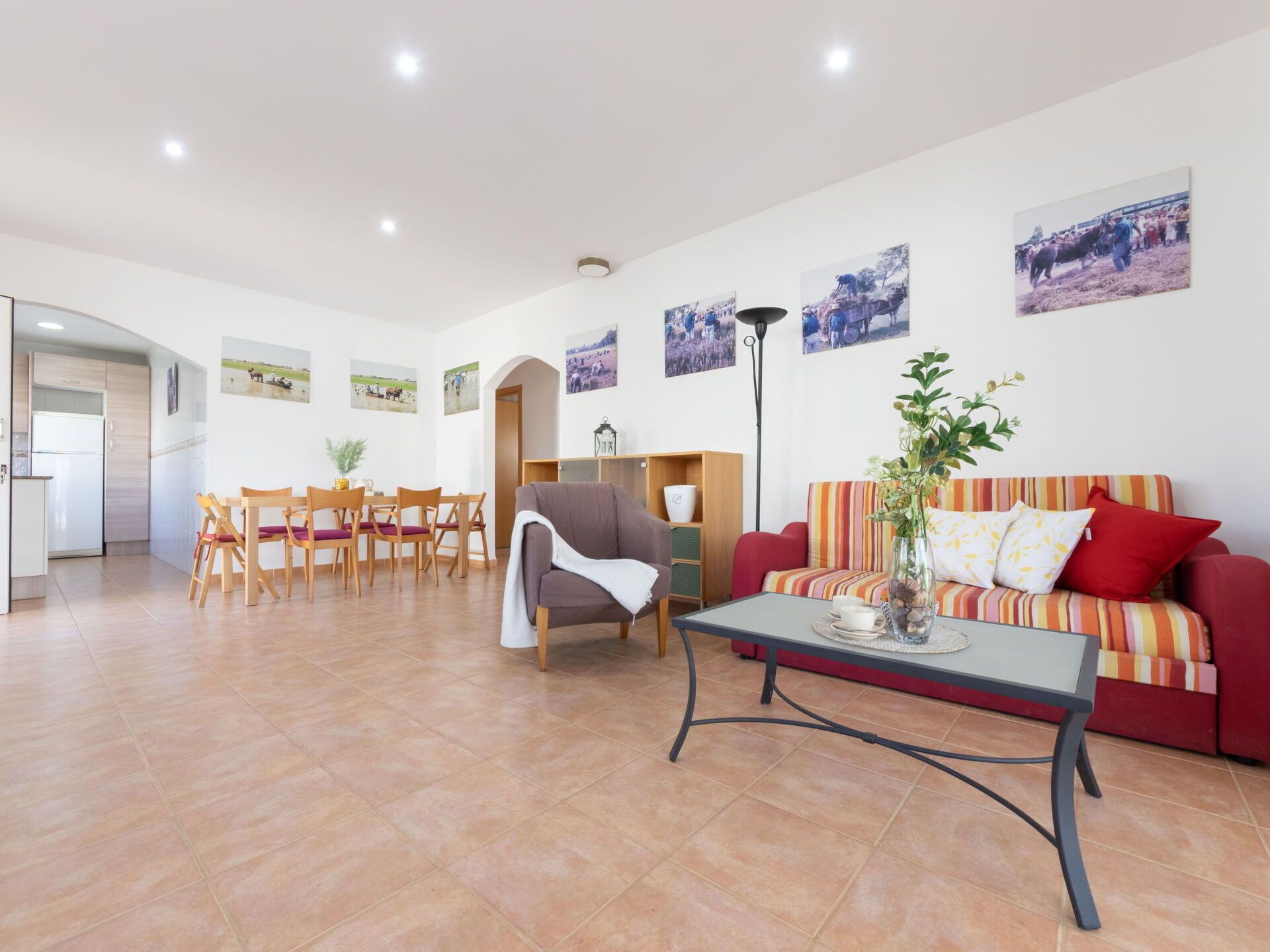 Un grand espace de vie comprenant un canapé, une table à manger et des chaises. On y trouve également des tableaux accrochés au mur et une lampe.