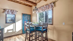 A dining area with a wooden table, blue cushioned chairs, and a window with floral curtains. - Charming 660 sq. ft. Sedona Meadowlark Studio with stunning red rock views! (Sedona)