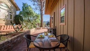 A patio with a glass table and chairs, a brick wall, and a view of a mountain range. - Charming 660 sq. ft. Sedona Meadowlark Studio with stunning red rock views! (Sedona)