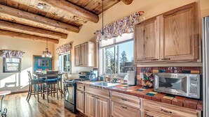 A spacious kitchen with wooden cabinets, a large island, and a dining area with a table and chairs. - Charming 660 sq. ft. Sedona Meadowlark Studio with stunning red rock views! (Sedona)