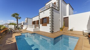 Una villa moderna con piscina, balcón y vistas del paisaje circundante.