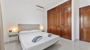 Un dormitorio con cama, mesitas de noche, aire acondicionado y armarios de madera.