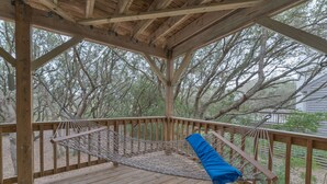 Eine Holzterrasse mit einer Hängematte und einem blauen Kissen.