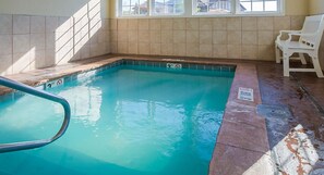 Swimmers can enjoy a refreshing dip in the pool, surrounded by a tiled wall and a shallow end with a depth indicator.