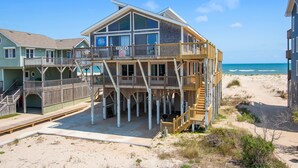 A beachfront property with a large wooden deck, multiple balconies, and a view of the ocean. - Oceanfront, Guest House, Hot Tub & Spacious Decks (Avon)
