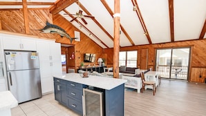 A spacious kitchen with wooden beams, a large island, and a dining area with a view. - Oceanfront, Guest House, Hot Tub & Spacious Decks (Avon)