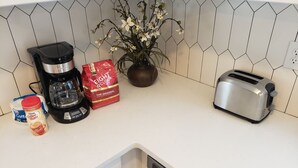 A kitchen counter with a coffee maker, a bag of coffee, a toaster, and a potted plant. - Southend Home walk 2 *Uptown Panthers Stadium Restaurants (Charlotte)