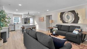 A modern living room with a grey sofa, a coffee table, and a large abstract painting on the wall. - Southend Home walk 2 *Uptown Panthers Stadium Restaurants (Charlotte)