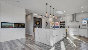 Une cuisine moderne dotée d’un îlot central, de luminaires suspendus et d’une grande fenêtre.