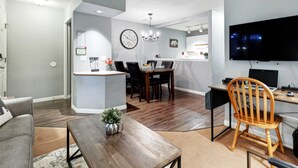 Una sala de estar moderna con comedor, una isla de cocina y un televisor de pantalla plana.
