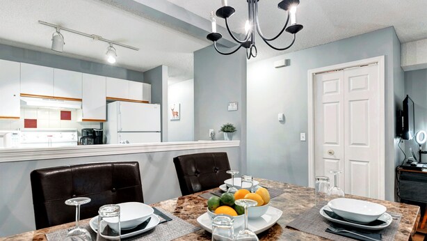 Un comedor moderno con una mesa de granito, sillas de cuero oscuro y una araña.