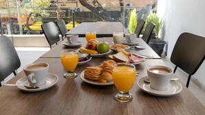 A breakfast table with coffee, orange juice, croissants, and fruit. - Hotel M (Mendoza)